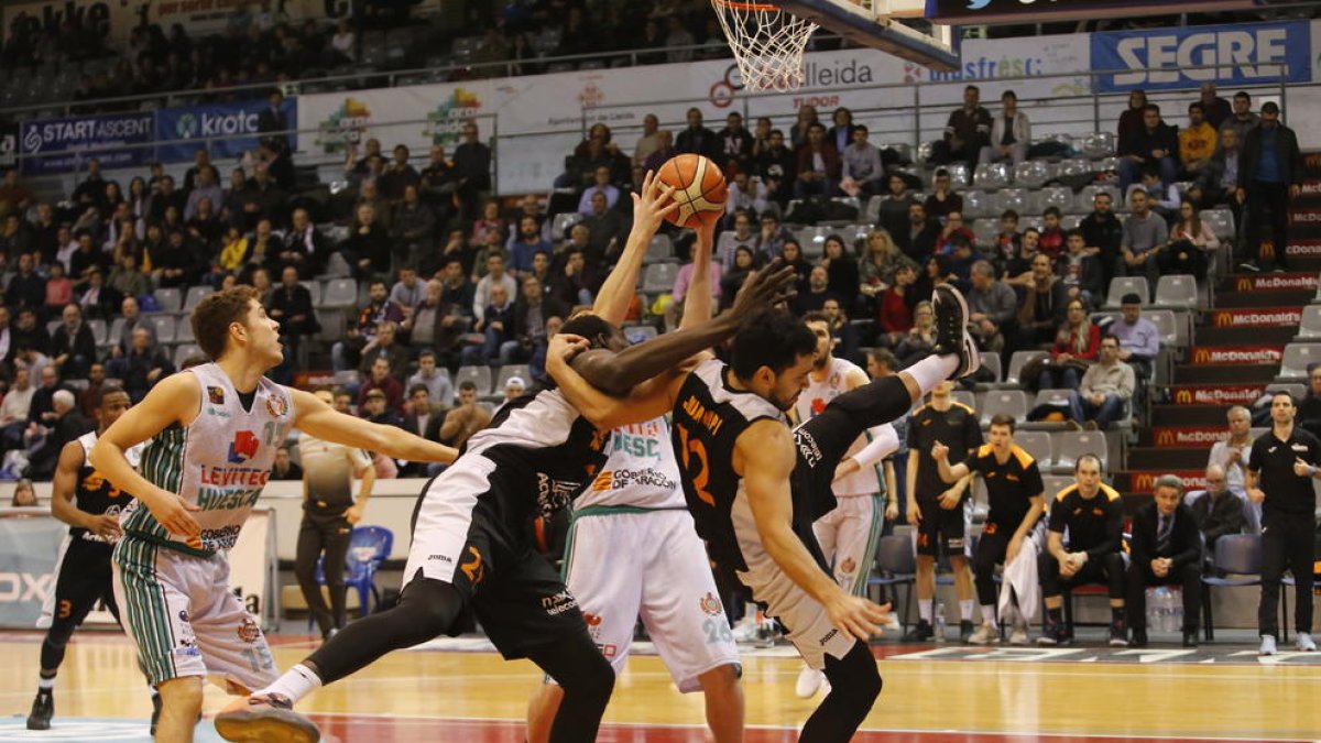 Ablaye Mbaye i Juampi Sutina lluiten per un rebot amb un jugador del Peñas Osca.