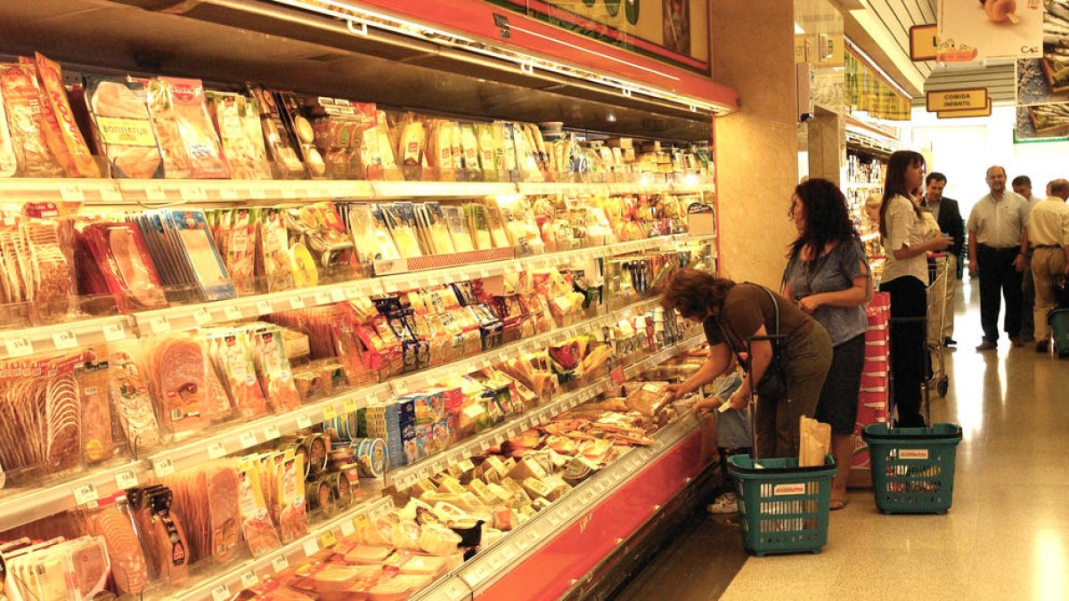 Imagen de archivo de varios clientes haciendo la compra en la sección de cárnicos refrigerados.