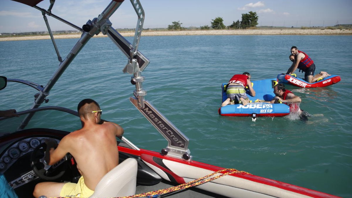 Un grup practica esports aquàtics a Gimenells i, a la imatge dreta, la vigilant de la zona de bany de Camarasa, que va començar a treballar ahir.