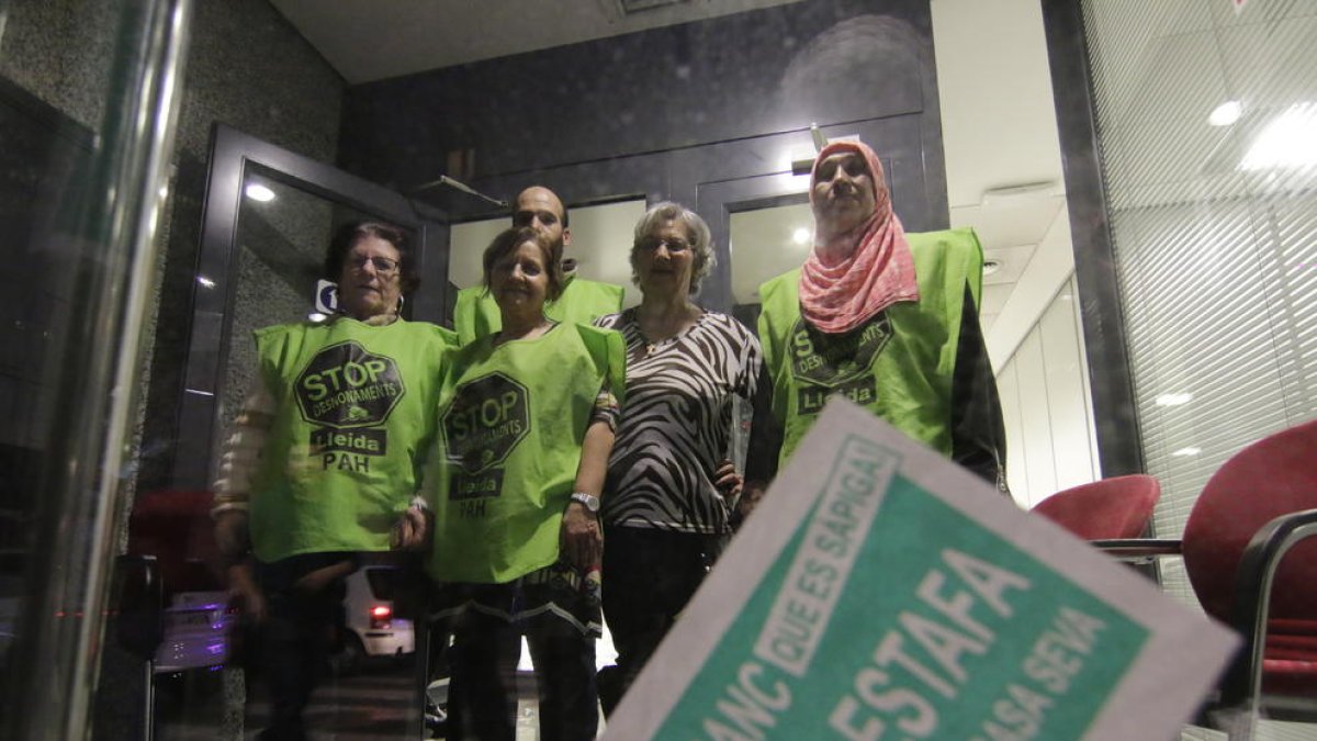 Miembros de la Plataforma de Afectados por la Hipoteca (PAH) ocupando un banco en Lleida.
