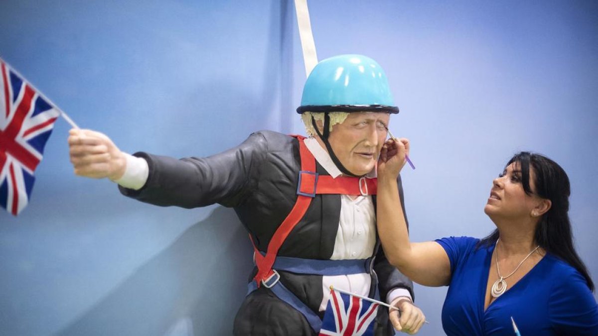 Una dona retoca un pastís que caricaturitza el ‘premier’ britànic.