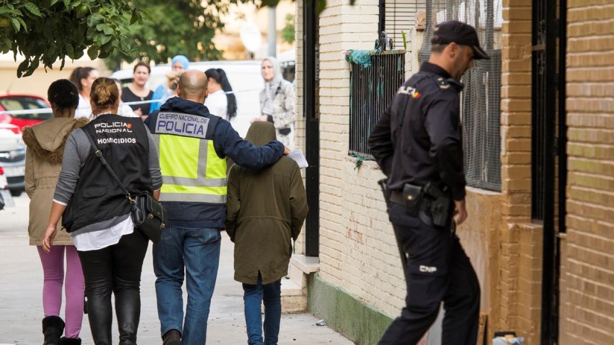 La Policía, con el niño que encontró el cuerpo de su madre, ayer.