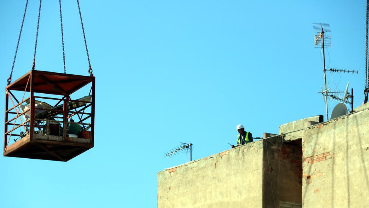 Els operaris que treballen en la demolició, ahir al terrat del bloc afectat.