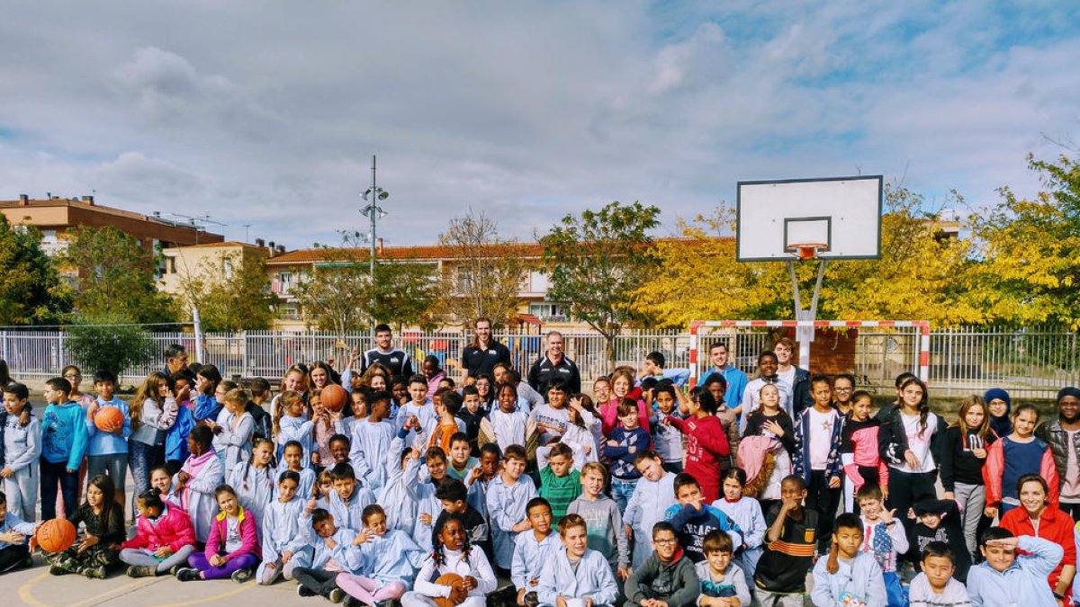 Los alumnos del IE Torre Queralt, junto a los jugadores del Força Lleida durante la visita del martes en el patio del centro educativo.