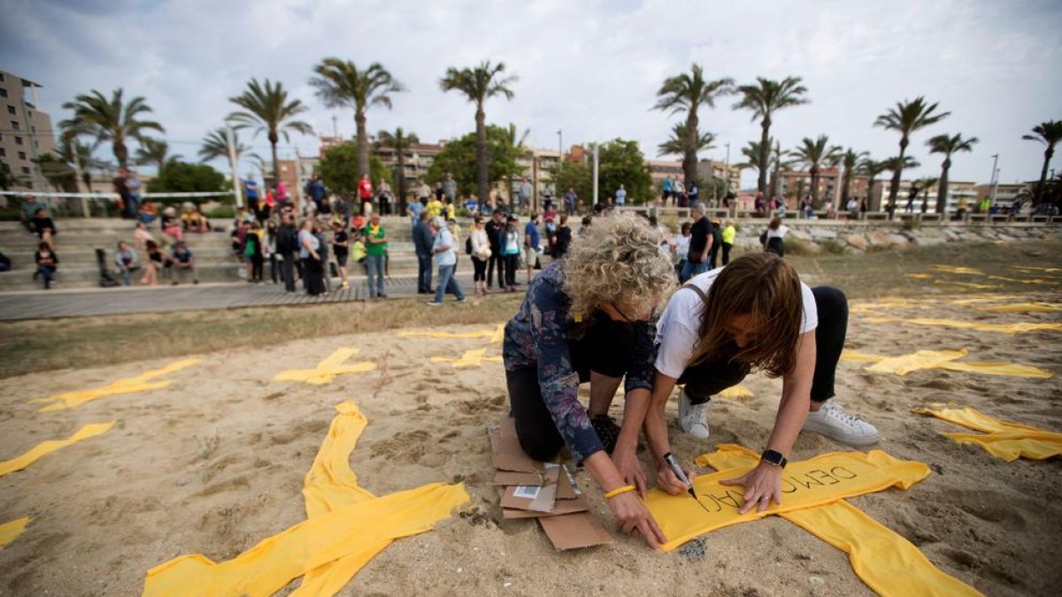 Dos joves col·loquen creus de tela grogues a la platja de Mataró, en una iniciativa del Comitè de Defensa de la República.