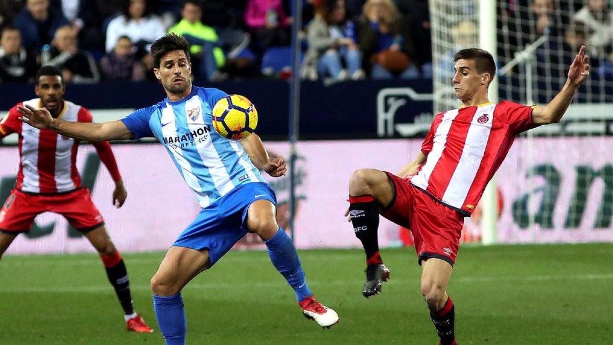 El centrecampista del Girona Pere Pons lluita una pilota amb el davanter Adrián durant el partit.
