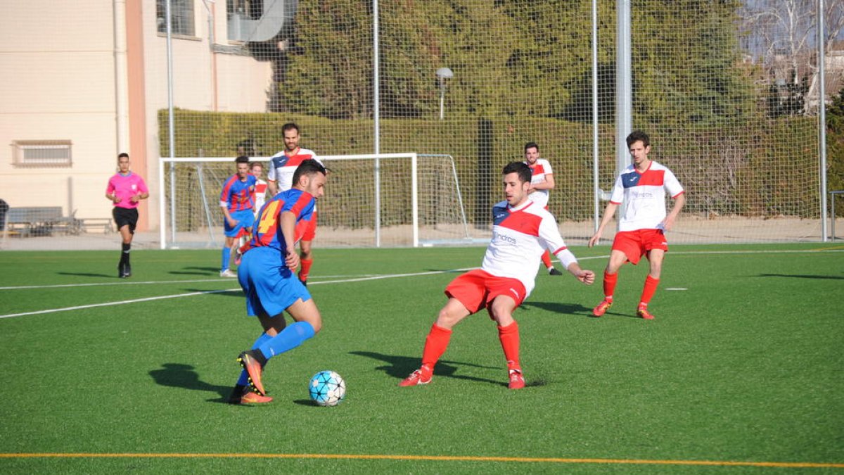 Un jugador del Térmens controla la pilota davant la presència de diversos defenses locals durant una acció del partit.