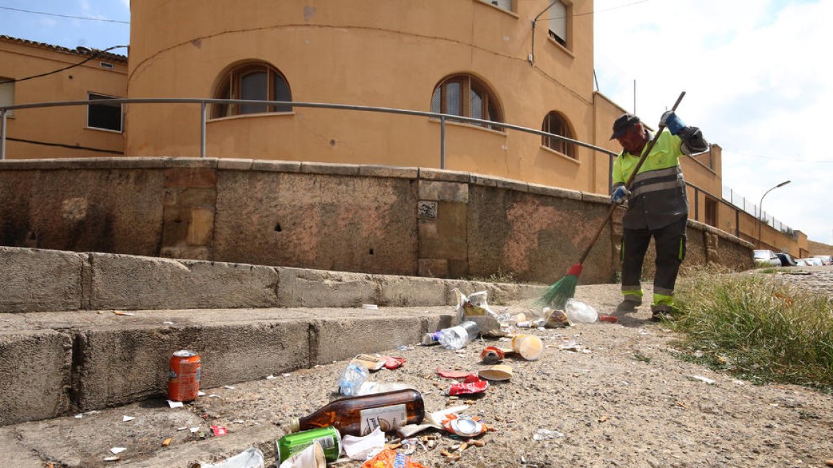 Imatge d’arxiu de tasques de neteja al carrer Sant Andreu de Lleida ple de botelles i llaunes de begudes.