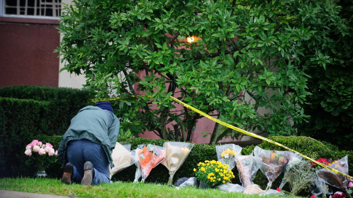 Un hombre coloca flores ante la sinagoga El Árbol de la Vida de Pittsburg, ayer.