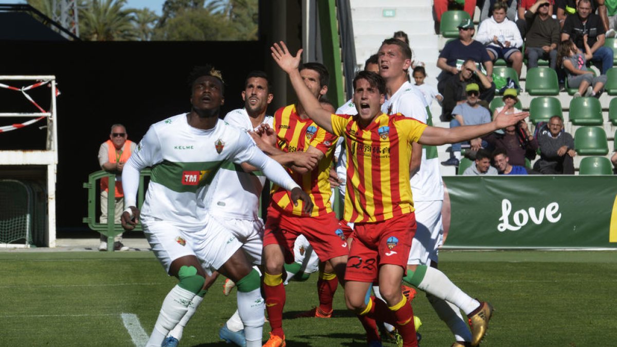 Juanto Ortuño reclama amb un gest obrint els braços entre un núvol de jugadors dels dos equips.