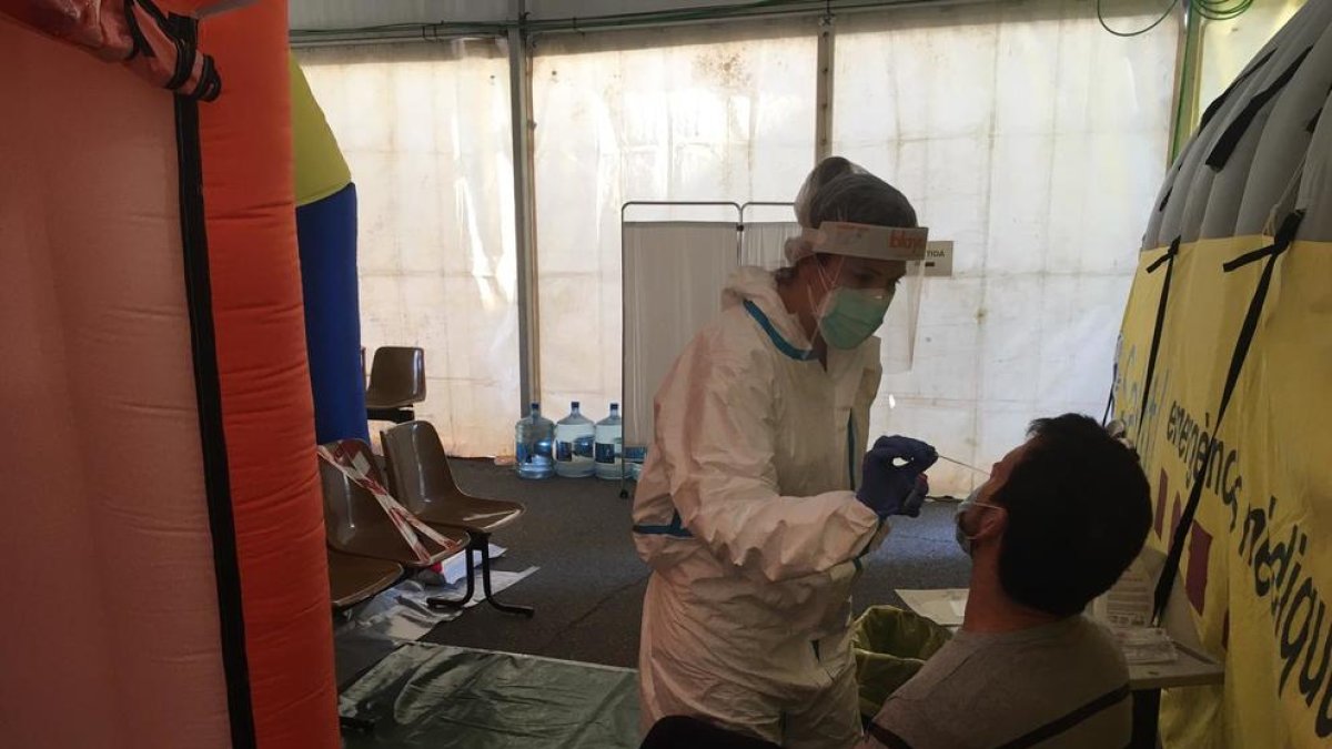 Una profesional sanitaria efectúa una prueba PCR a un paciente en la carpa frente al CAP de Prat de la Riba.