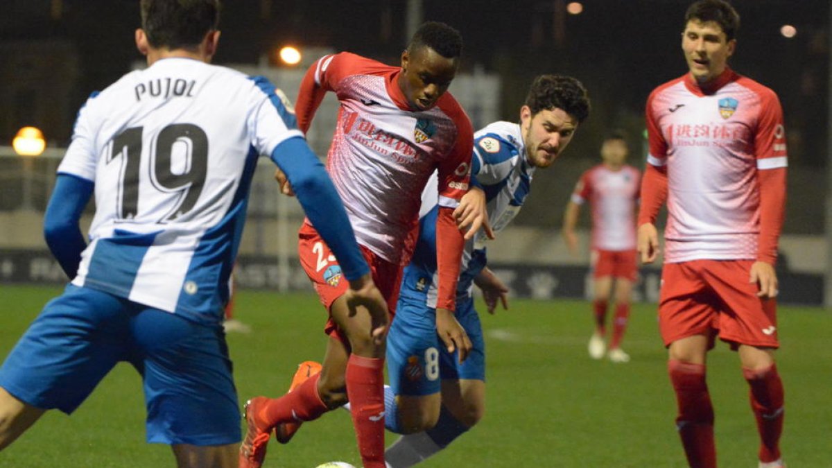 Cano conduce el balón ante la oposición de dos jugadores del Espanyol B.