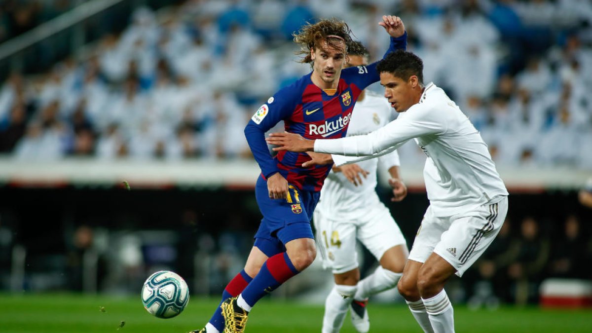 El azulgrana Antoine Griezmann intenta escapar de la presión de su compatriota Raphael Varane.