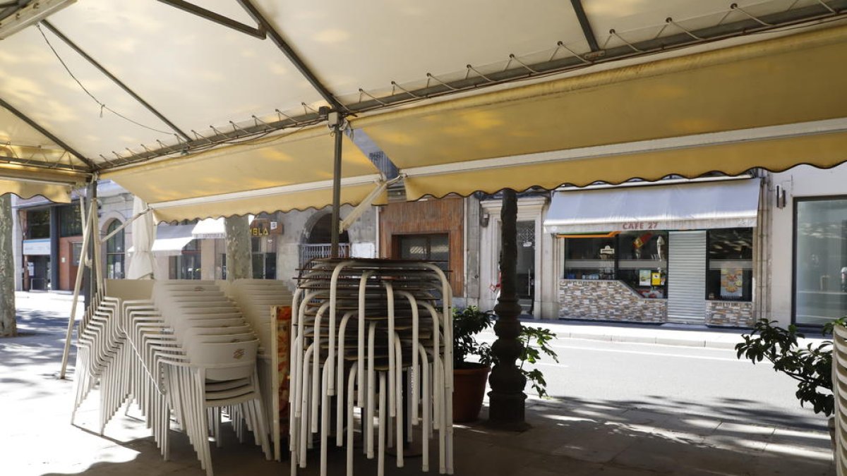 Sillas apiladas en la terraza de un bar cerrado en la Rambla Ferran de Lleida.