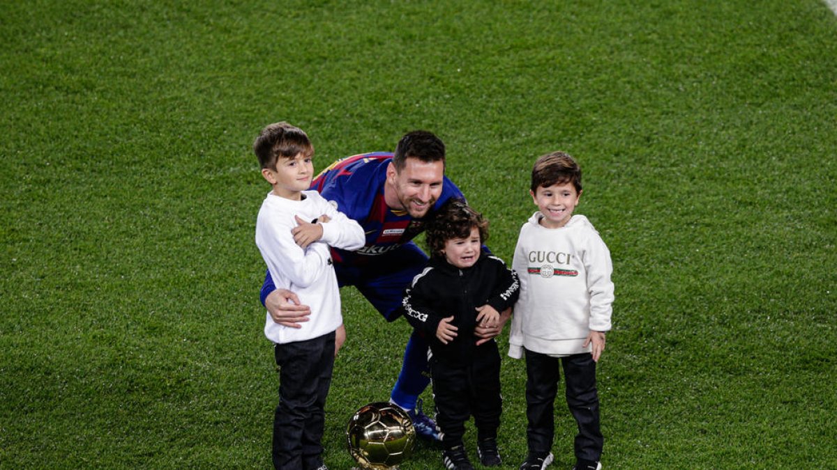 Leo Messi posa junto a sus tres hijos en el césped del Camp Nou tras ofrecer el sexto Balón de Oro de su carrera a la afición.