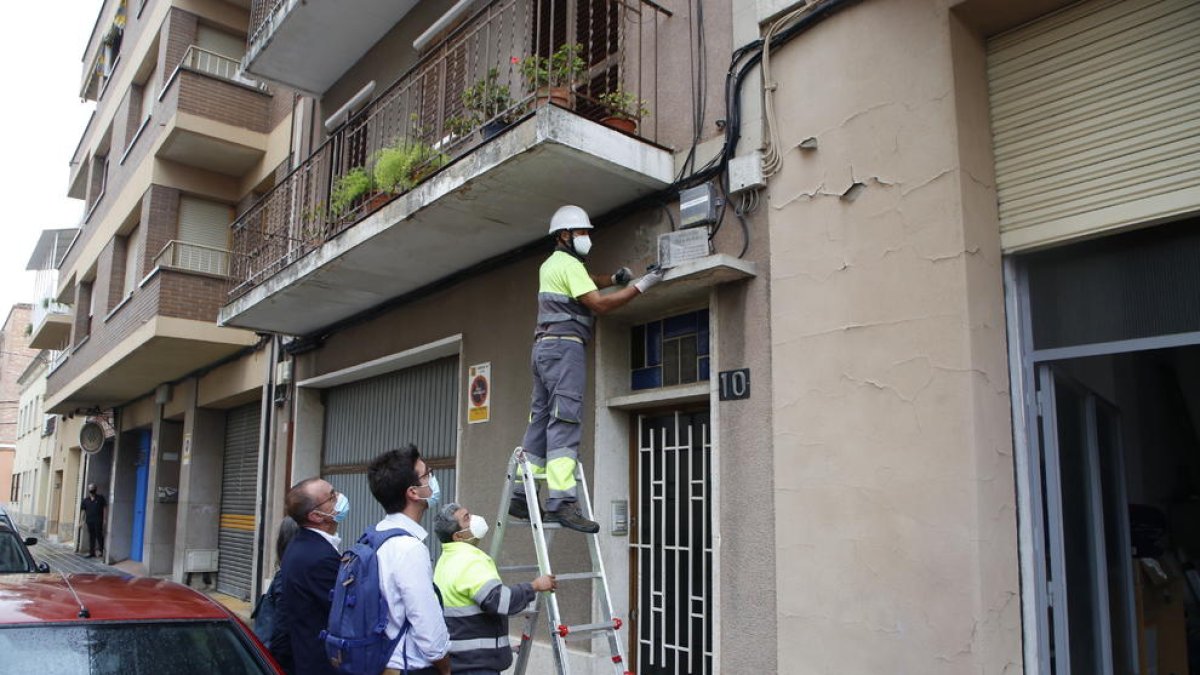 Un operari retira la placa franquista d’un bloc de Sant Jaume davant la mirada de Postius i Pueyo.