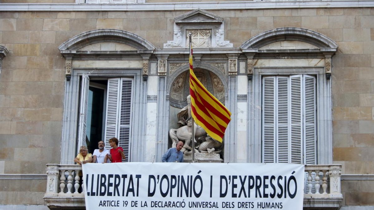 El cantautor i exdiputat Lluís Llach, l'actriu Sílvia Bel, el periodista i exdiputat Antoni Baños i la portaveu de Somescola, Teresa Casals, col·loquen una nova pancarta al balcó del Palau de la Generalitat.