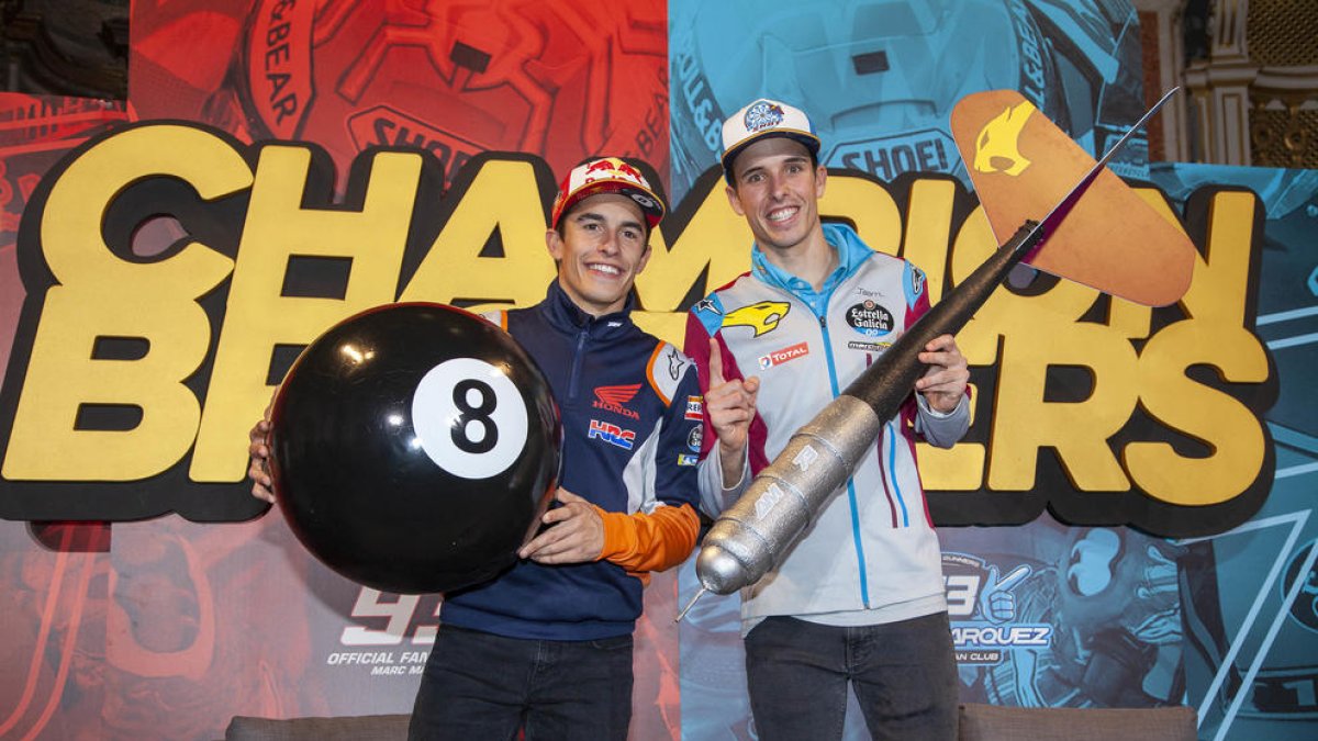 Marc y Àlex, con la bola número 8 de billar y el dardo, delante de una gran pancarta con la leyenda ‘Champion Brothers’.