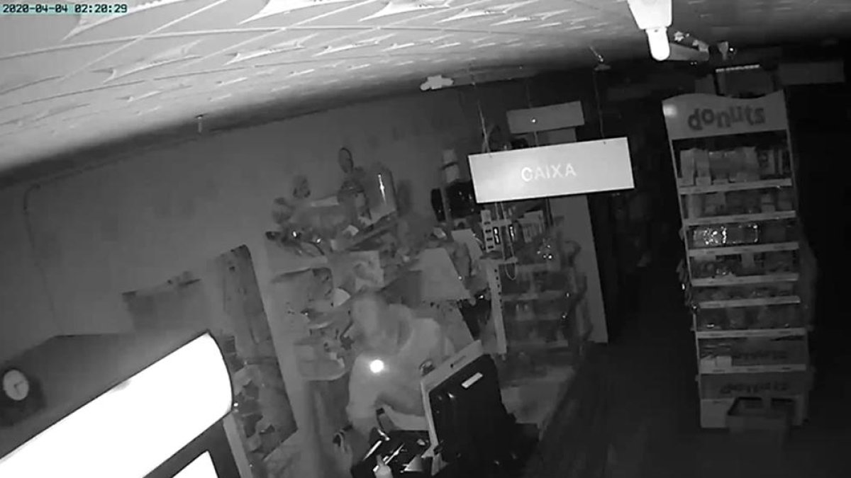Imagen del ladrón, que llevaba un linterna en la boca, con el cajón abierto de la máquina registradora.