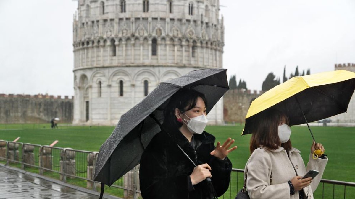 Turistas con mascarilla paseando por los alrededores de la Torre de Pisa.