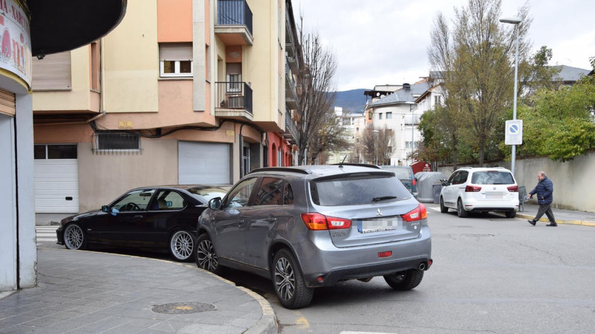 Dos vehículos estacionados en una intersección coloreada en amarillo como señal de prohibición.
