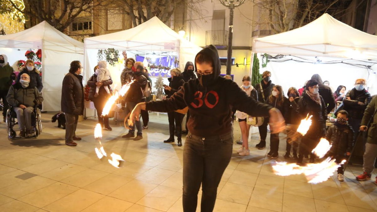 Espectáculo de fuego ayer en el mercado navideño de Mollerussa. A la derecha, una de las paradas con motivos navideños en el Mercat de Santa Llúcia de Lleida.