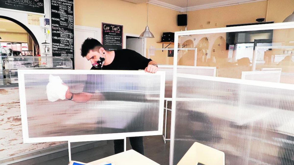 L’amo d’un bar restaurant de Lleida prepara l’interior del local amb mampares entre les taules.