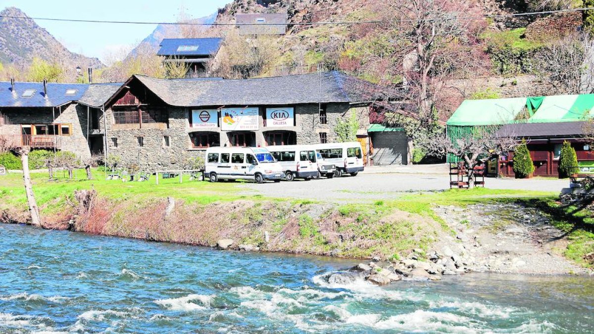 El riu Noguera Pallaresa i al fons, una empresa d’esports d’aventura amb les furgonetes aturades.