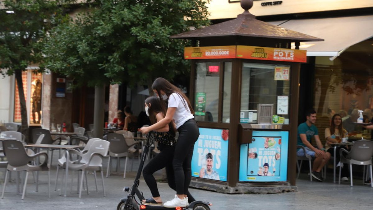 Dos jóvenes circulando en patinete eléctrico por el Eix, ayer.