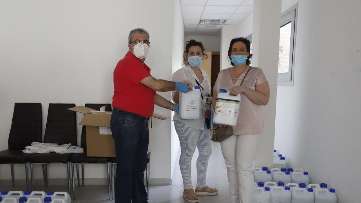 A l’esquerra, el president de l’Eix, Llorenç González, entrega el kit sanitari a una comercianta. A la dreta, una dona surt d’una botiga que ofereix serveis de cita prèvia.