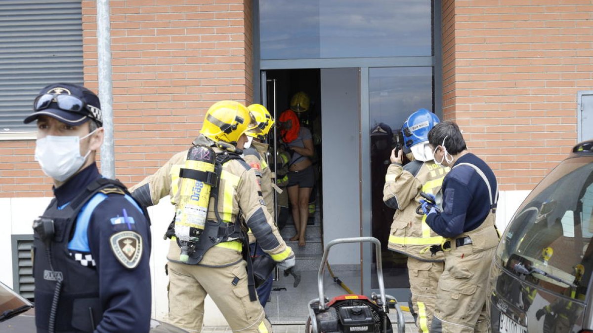 Momento en el que los bomberos sacaron a la mujer de la vivienda (i) y del amplio dispostivo desplegado (d).