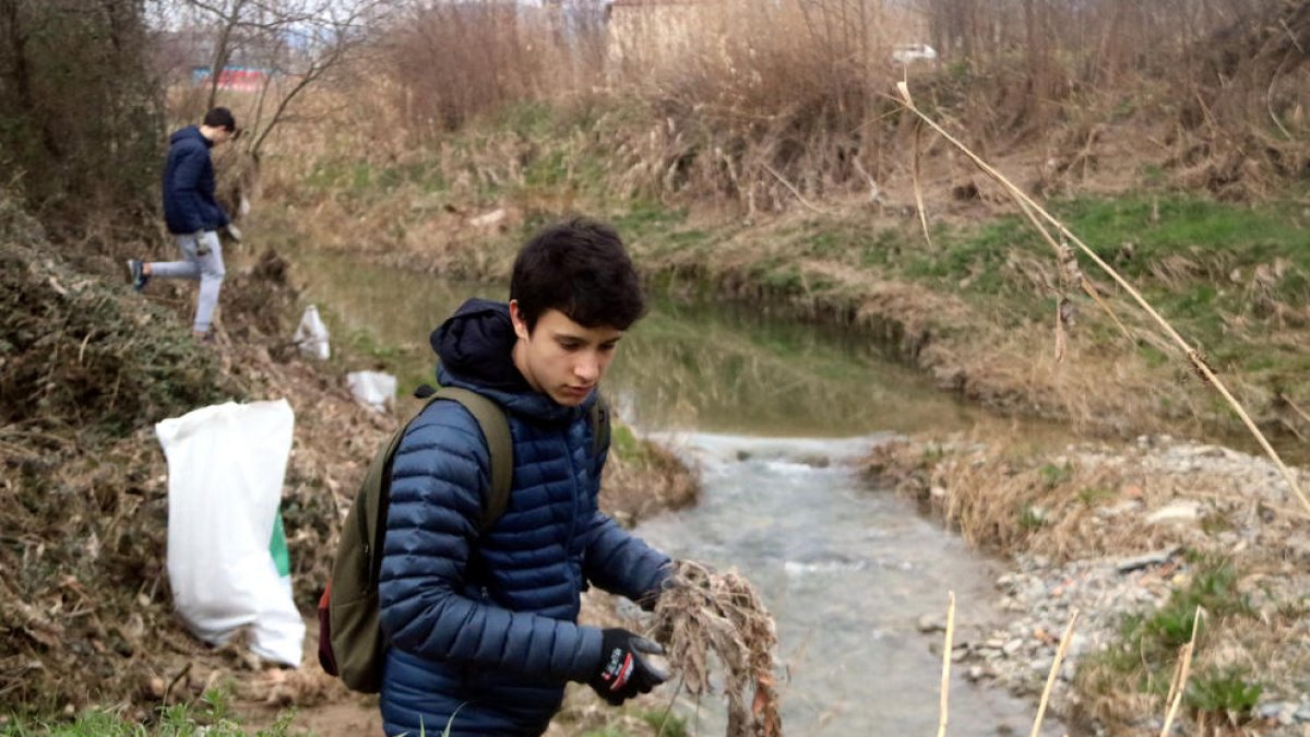 Un jove retira escombraries del curs del riu Mèder de Vic.