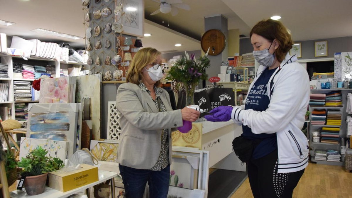 Una comerciante de La Seu desinfectando ayer las manos de una clienta de su tienda.