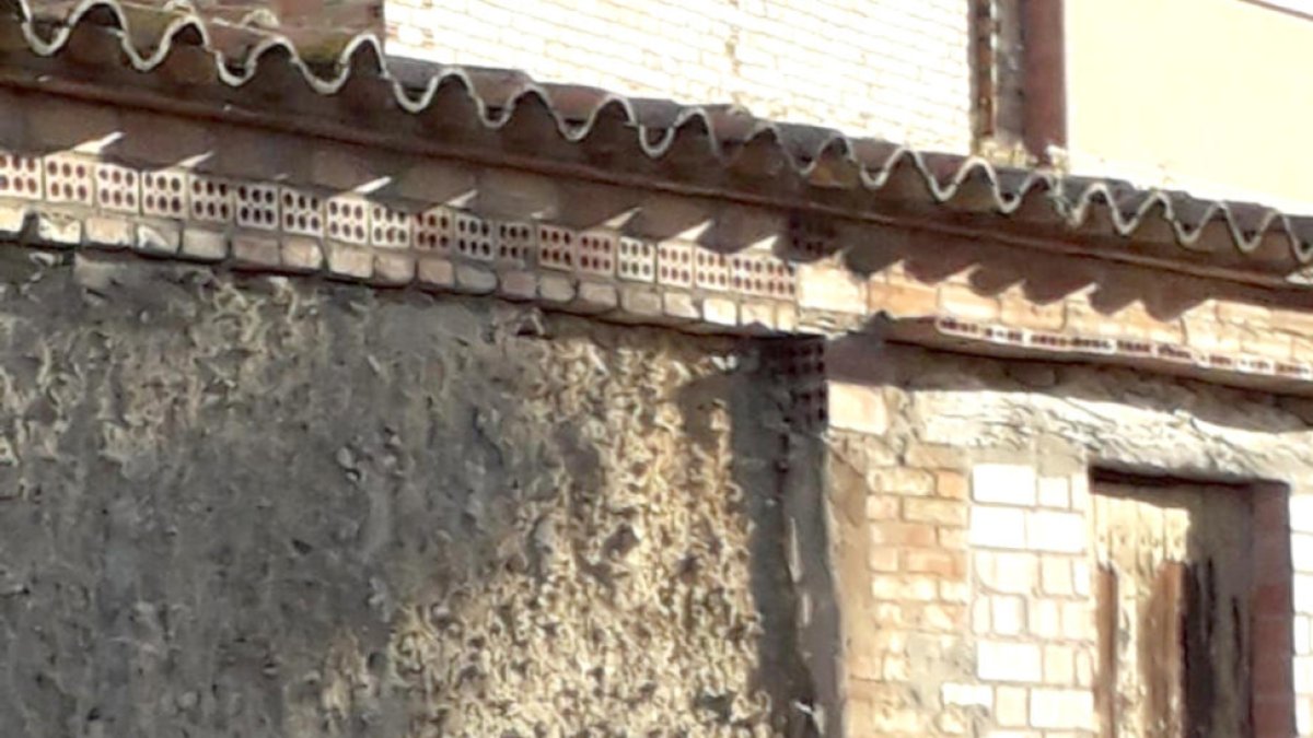 Dos jóvenes con taburetes del bar Rasep, cerrado, en La Granja d’Escarp.