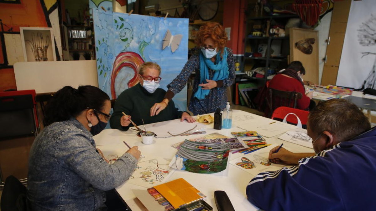 Rosa Franco, de la Escola Traç de Lleida, con usuarios del club social La Brúixola en un taller de arte.