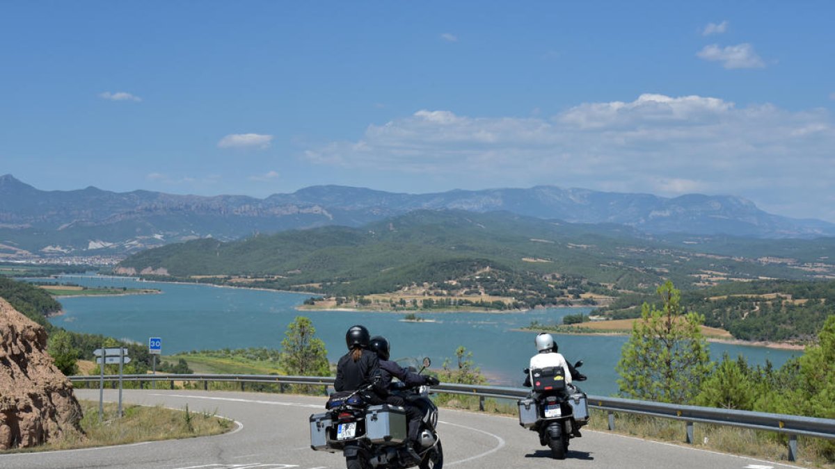Motoristas pasando por el pantano de Rialb.