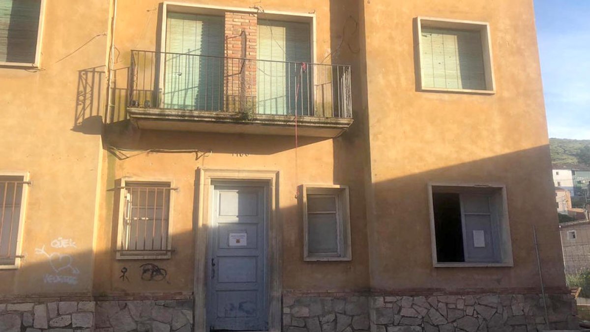 Dos jóvenes con taburetes del bar Rasep, cerrado, en La Granja d’Escarp.