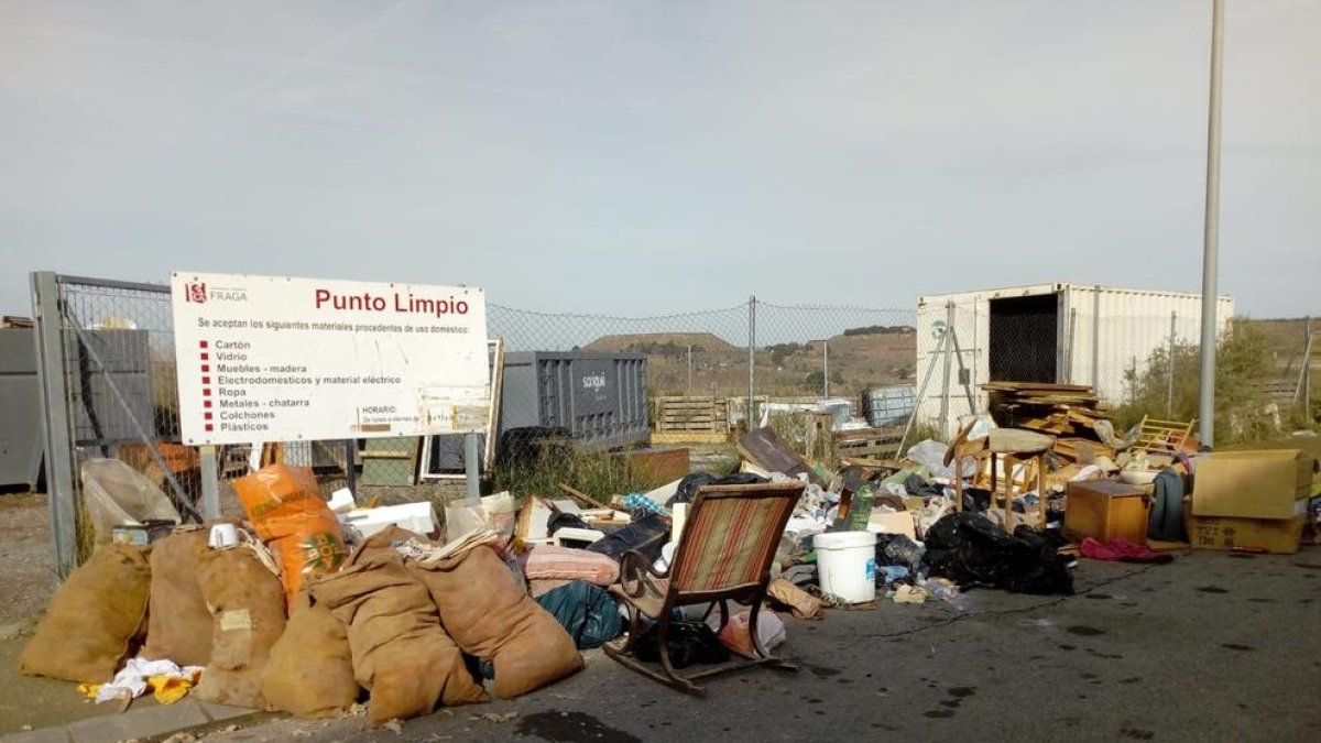 El punto limpio lleno de basura en la puerta del recinto.