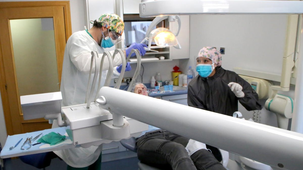 Dos professionals d’una clínica dental de Lleida ciutat atenent un pacient ahir a la tarda.