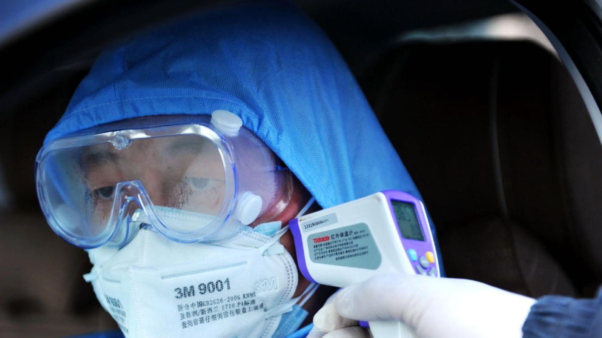 Un sanitari pren la temperatura a un ciutadà de Qingdao.
