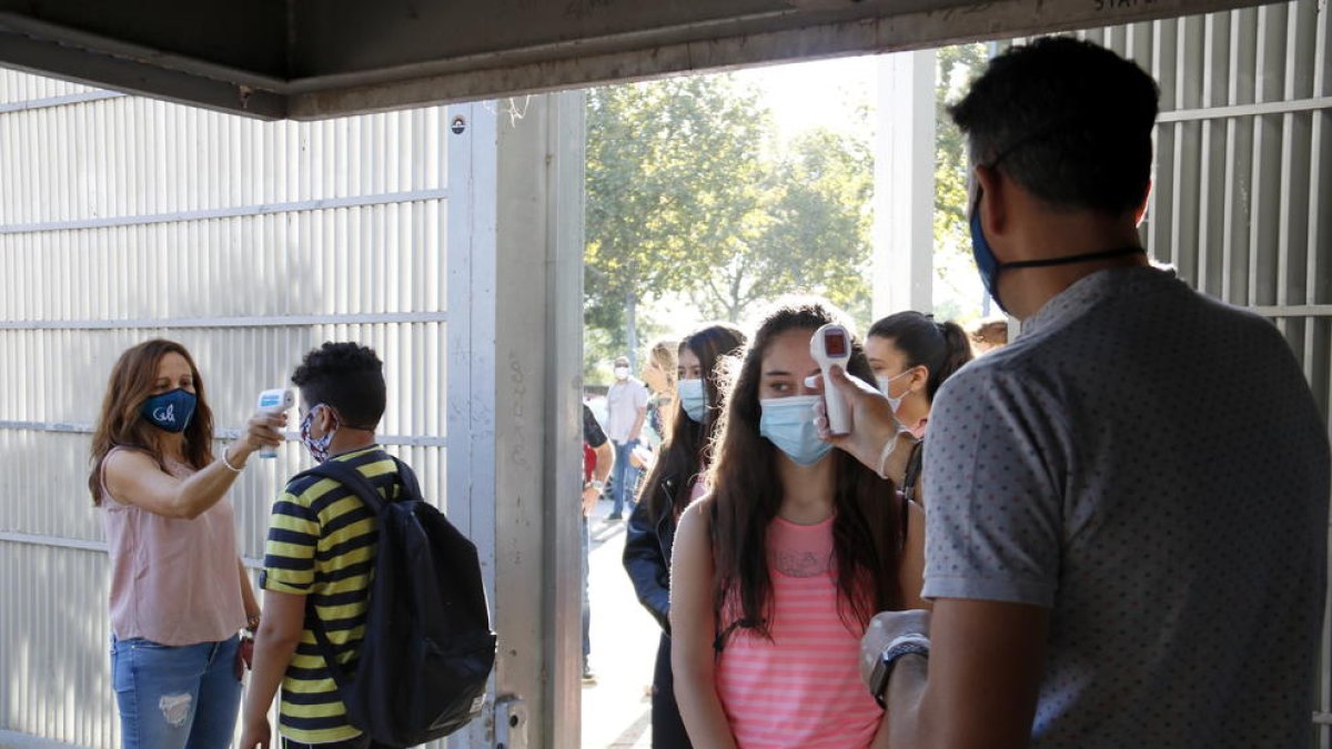 Profesores del instituto Gili i Gaya toman la temperatura a los alumnos en el acceso al centro.