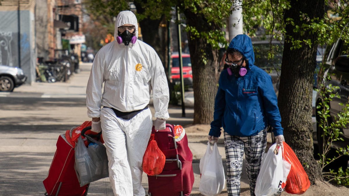 Dos personas en Nueva York con medidas de protección tras ir a comprar al supermercado.