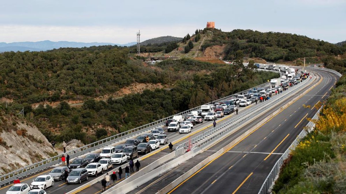 Camiones y coches bloqueados en La Jonquera, y manifestantes caminando por la vía, ayer.