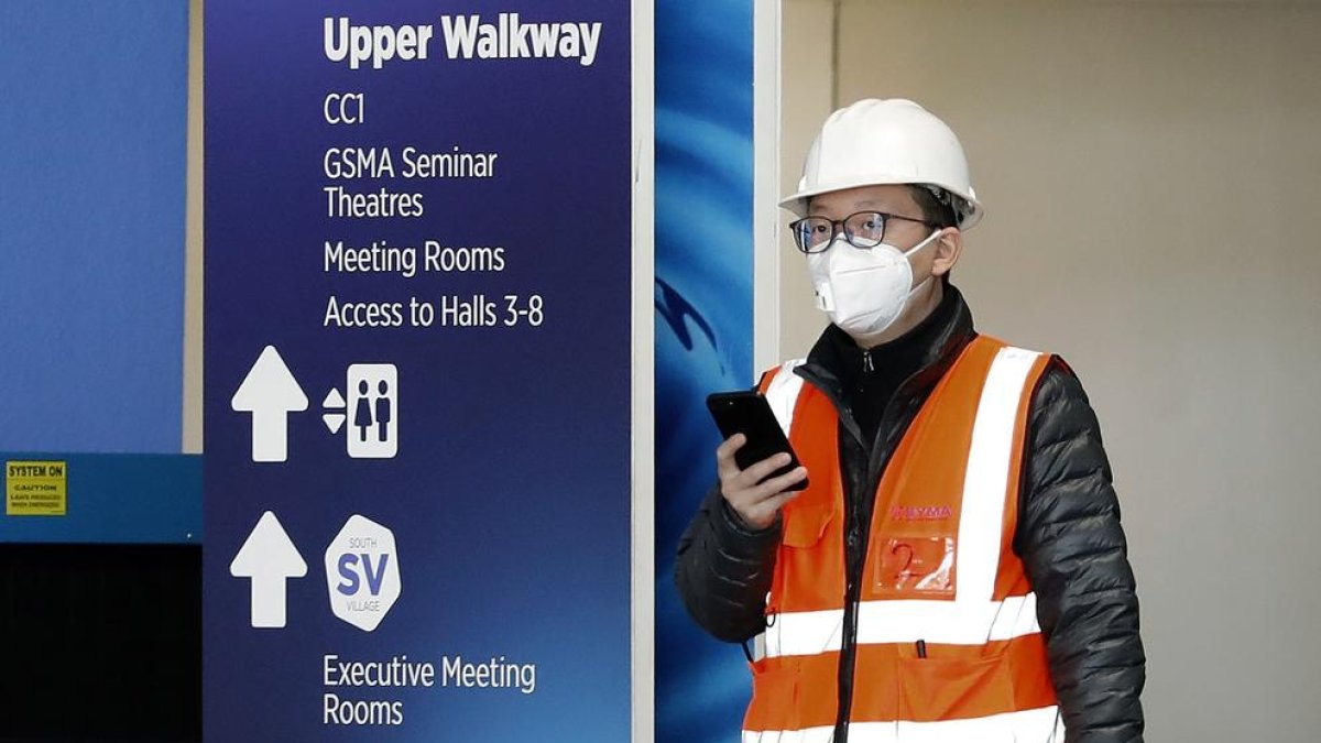 Un trabajador, con mascarilla, sale del recinto ferial de Gran Via, donde se iba a celebrar el Mobile.