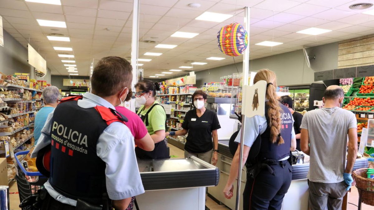 Una parella de Mossos ahir a l’interior d’un dels establiments comercials d’Aitona.