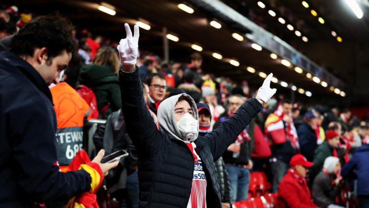 Un aficionado del Atlético, con mascarilla y guantes, celebra la clasificación del Atlético en Anfield.