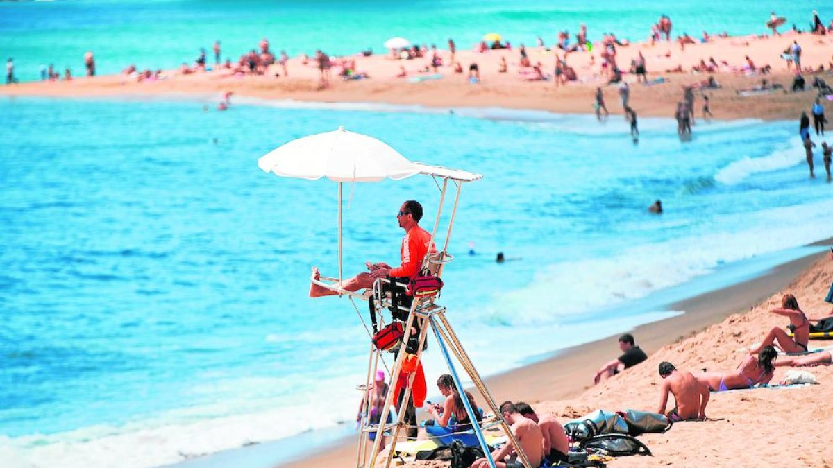 Varias personas disfrutando ayer del sol en una playa de Barcelona.