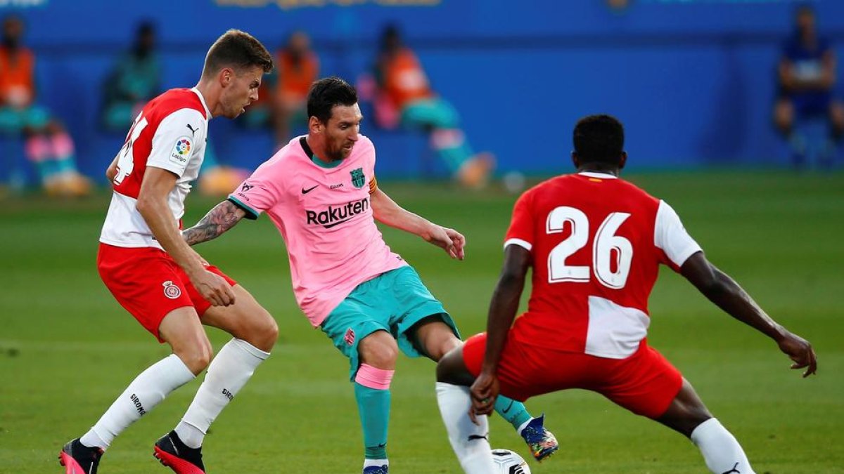 Leo Messi controla el balón ante Gumbau e Ibrahim Kebe, jugadores del Girona.