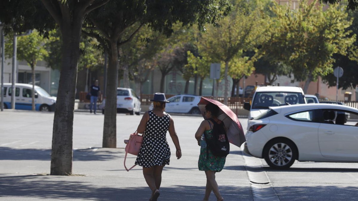 Dos viandantes protegiéndose del sol en Lleida, donde el termómetro superó los 34 grados.