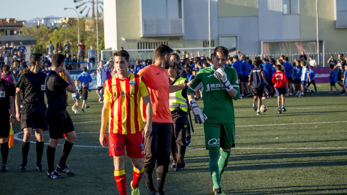 Jugadores del Lleida se dirigen, abatidos, hasta los vestuarios, mientras que al fondo la plantilla y la afición local celebran que son campeones de grupo.